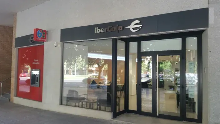 Entrada a una oficina de Ibercaja con cajero automático y rótulo corporativo en la fachada.