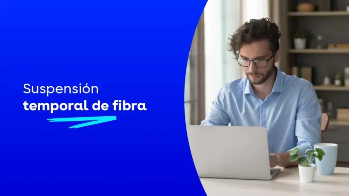 Hombre trabajando en casa con portátil y mensaje de suspensión temporal de fibra óptica de DIGI.