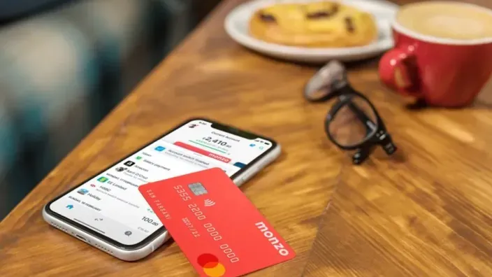 Tarjeta Monzo junto a un teléfono móvil sobre una mesa de cafetería