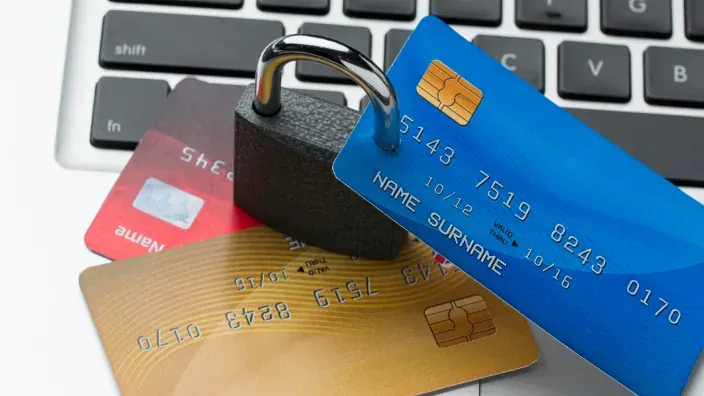 Varias tarjetas de crédito junto a un candado sobre un teclado de ordenador, representando la seguridad en pagos online.