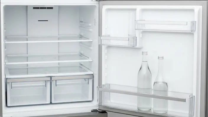 Nevera vacía y limpia con la puerta abierta, un consejo para ahorrar energía y evitar malos olores antes de ir de vacaciones.