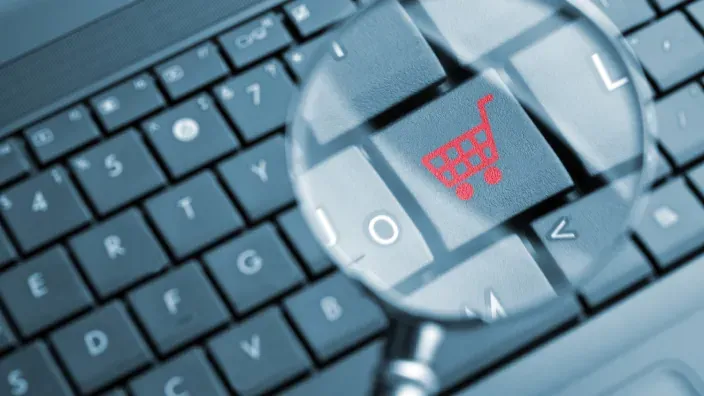 Teclado con un icono de carrito de compra visto a través de una lupa