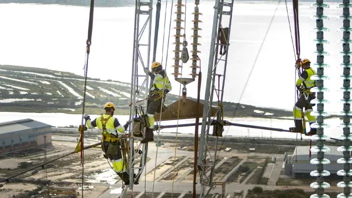 Técnicos realizando labores de mantenimiento en una torre de alta tensión eléctrica