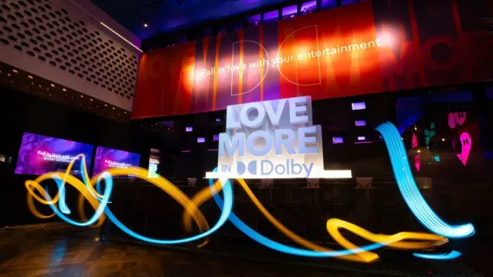 Espacio promocional de Dolby con iluminación dinámica que representa la mejora de la experiencia audiovisual en cine y entretenimiento.