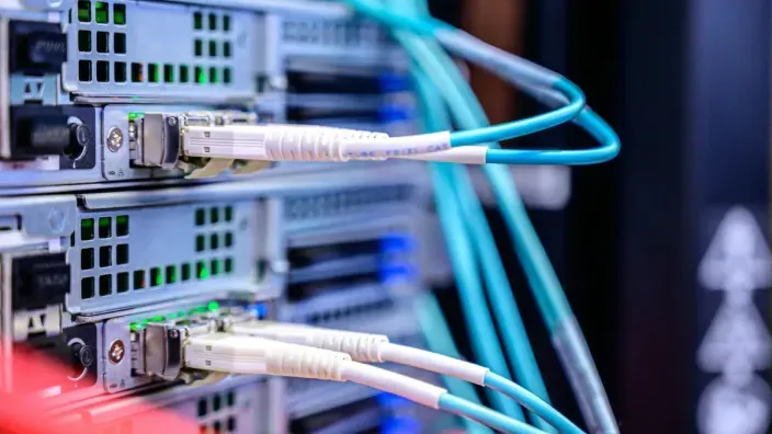 Primer plano de cables de fibra óptica conectados a un switch de red en un centro de datos.