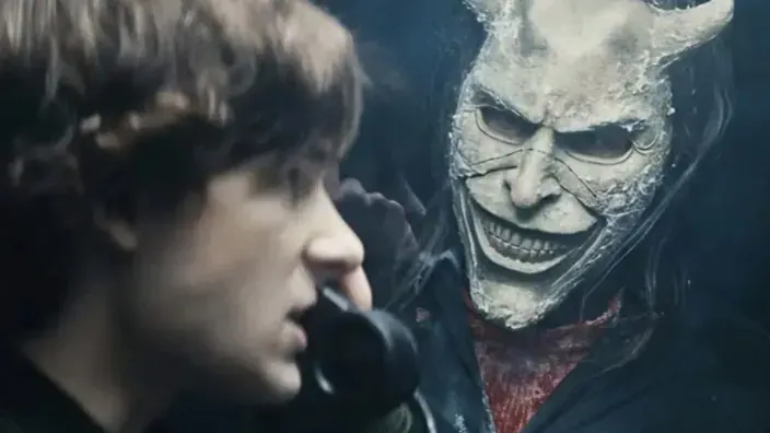 El secuestrador con una máscara de demonio sonriente acecha a su víctima en una escena de la película de terror Black Phone.