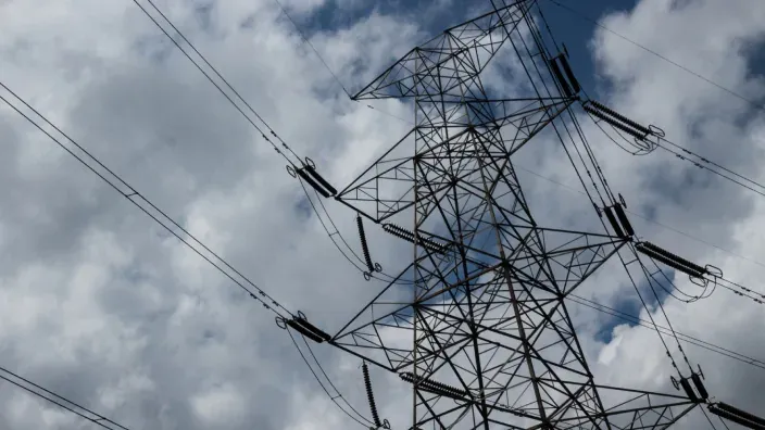 Torre de alta tensión con líneas eléctricas y cielo nublado