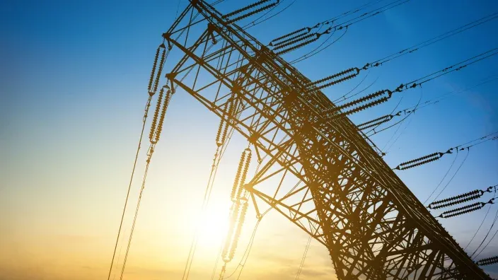 Torre eléctrica de alta tensión con cables al atardecer.