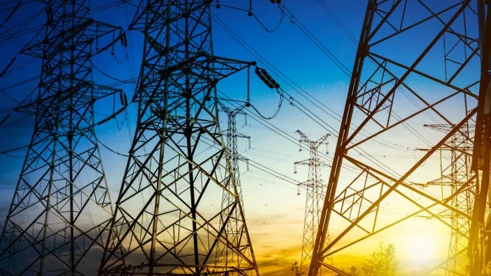 Torres de alta tensión de la red eléctrica con cables de transporte de energía al atardecer