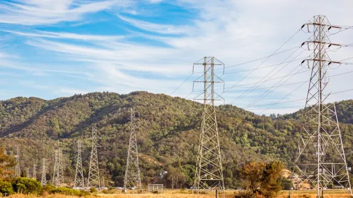Torres de alta tensión y líneas eléctricas atravesando una zona montañosa con vegetación