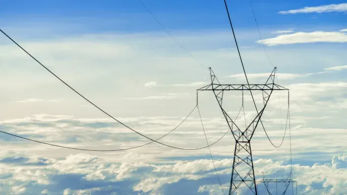 Torres eléctricas de alta tensión sobre un cielo despejado con nubes.