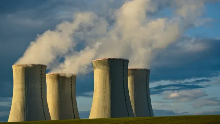 Torres de refrigeración de una central nuclear emitiendo vapor sobre un paisaje rural.