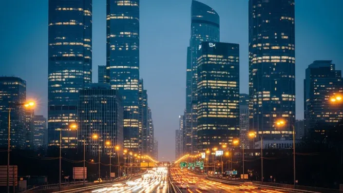 Rascacielos iluminados al anochecer con tráfico en una gran avenida.