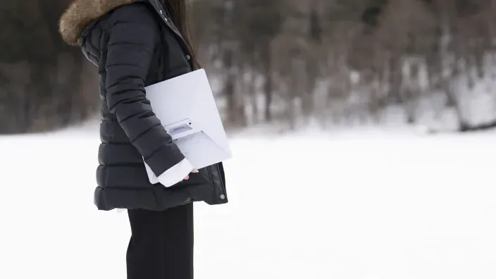 Persona con abrigo llevando una antena de Starlink en un entorno nevado para conexión a internet en climas extremos.