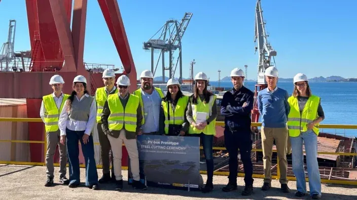 Grupo de técnicos y directivos de Naturgy con chalecos reflectantes y cascos posando en un astillero durante la ceremonia de corte de acero del prototipo PV-bos.