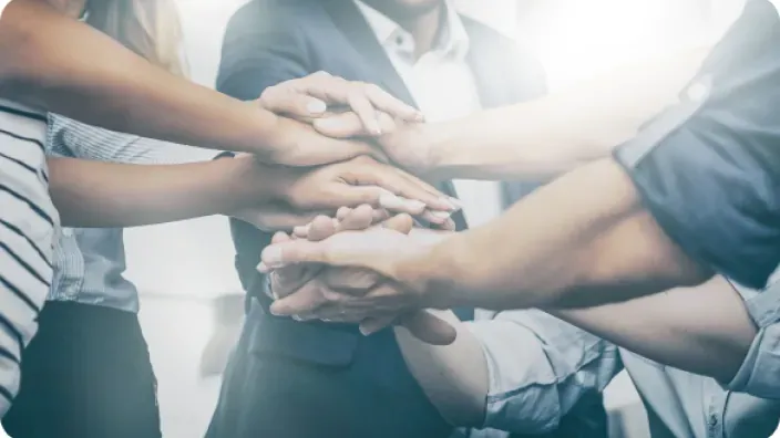 Manos de personas unidas como símbolo de colaboración y alianza estratégica empresarial.