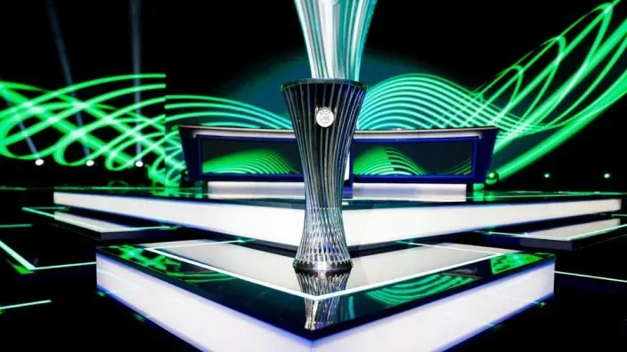Trofeo oficial de la UEFA Conference League sobre un escenario iluminado en verde