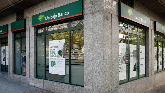 Exterior de una sucursal de Unicaja Banco con carteles informativos en los escaparates.