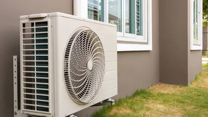 Unidad exterior de aire acondicionado instalada en la fachada de una vivienda.