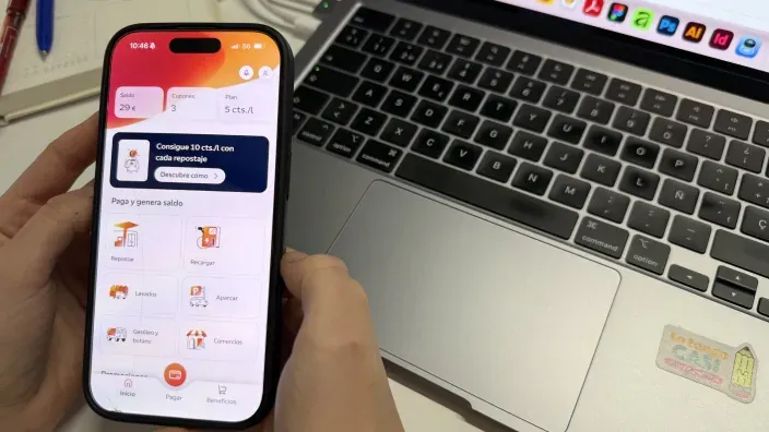Persona utilizando la aplicación Waylet en su smartphone junto a un ordenador portátil.