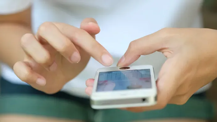 Manos interactuando con un teléfono móvil mediante pantalla táctil.