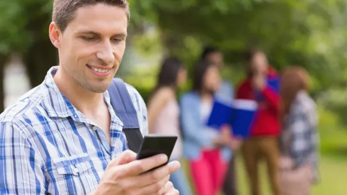 Joven estudiante usando su smartphone al aire libre.