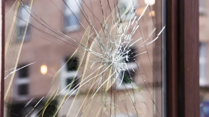 Cristal de ventana roto por un impacto en una vivienda, con grietas visibles en el vidrio