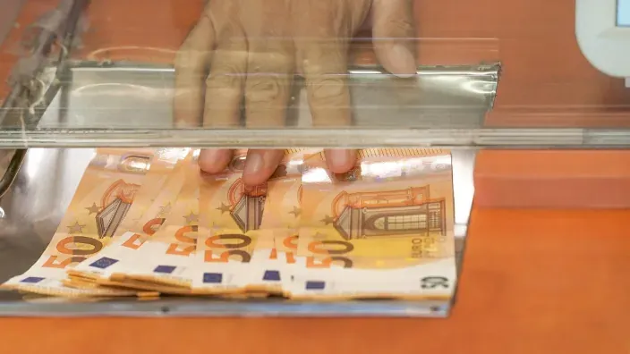 Dispensador de billetes de 50 euros en efectivo en ventanilla bancaria de seguridad.