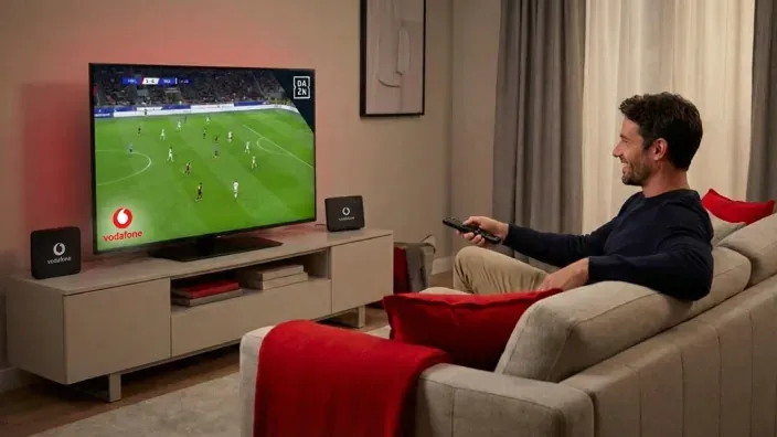 Hombre viendo partido de fútbol de DAZN en Vodafone TV con decodificador 4K en el salón.