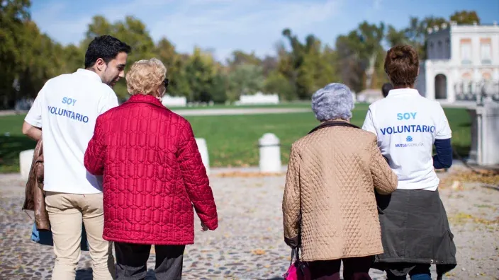 Voluntarios de Mutua Madrileña paseando al aire libre junto a personas mayores.