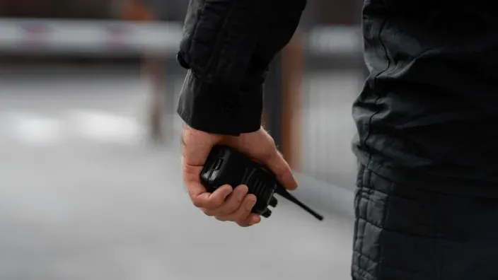 Guardia de seguridad con walkie-talkie para vigilancia y comunicaciones en un evento masivo.