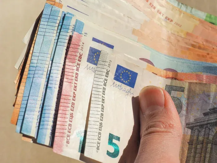Mano sosteniendo un abanico de billetes de euro de 5, 10, 20 y 50 para pagos en efectivo.