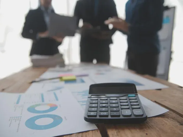 Asesores financieros analizando gráficos de inversión y rentabilidad en una mesa de oficina con calculadora.