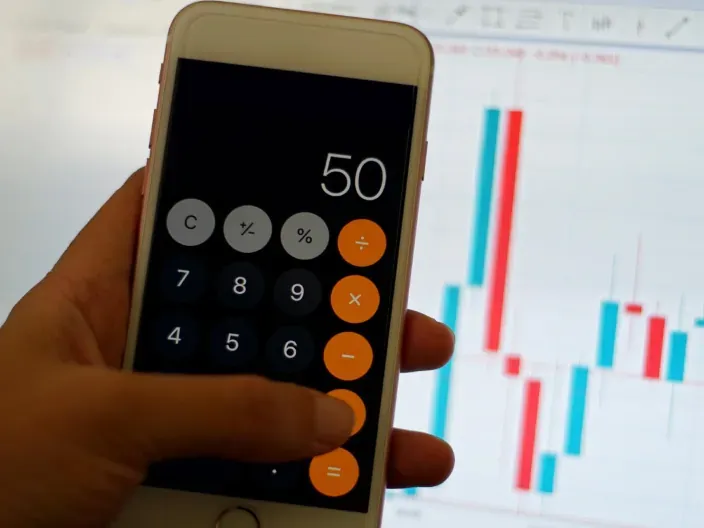 Mano usando calculadora en smartphone para saber cuánto sube una tarifa.