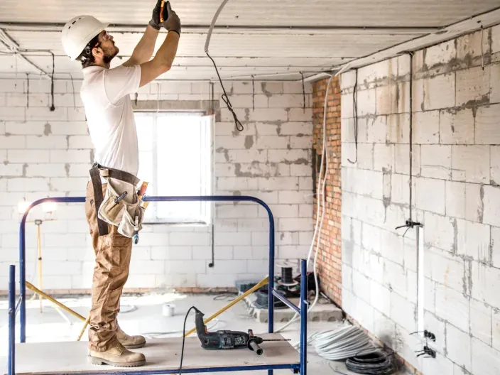 Electricista con casco trabajando en una instalación interior en obras