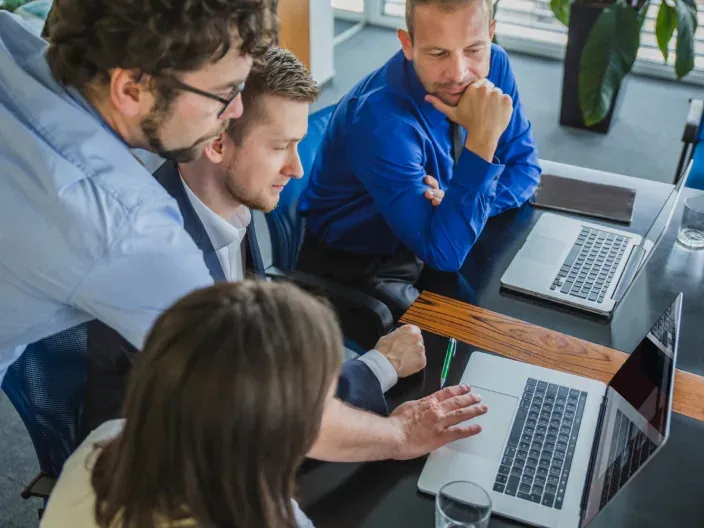Equipo de trabajo colaborativo en una formación tecnológica frente a un ordenador portátil en la oficina.