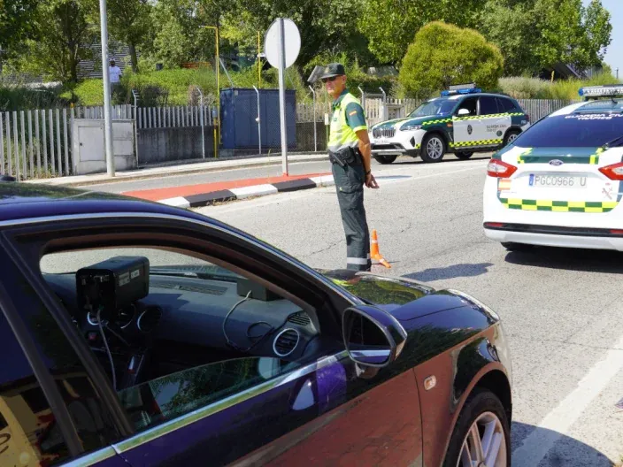 Agente de la Guardia Civil de Tráfico realizando un control en carretera junto a varios vehículos oficiales.