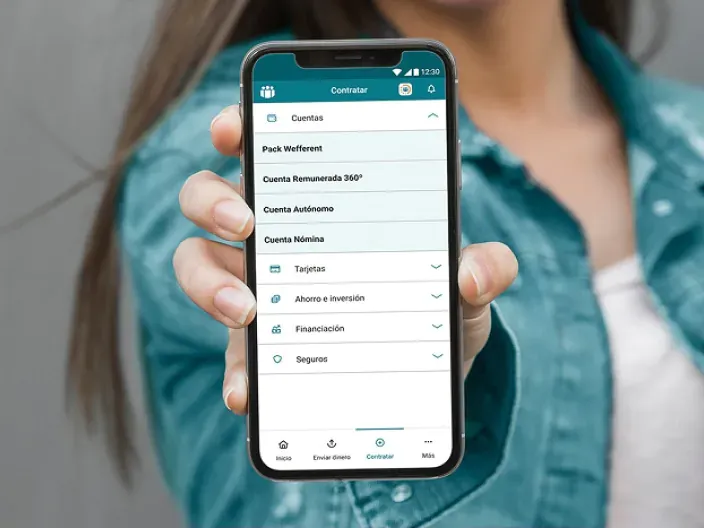 Persona sosteniendo un móvil con la app de Cajamar abierta en la sección de contratación de productos