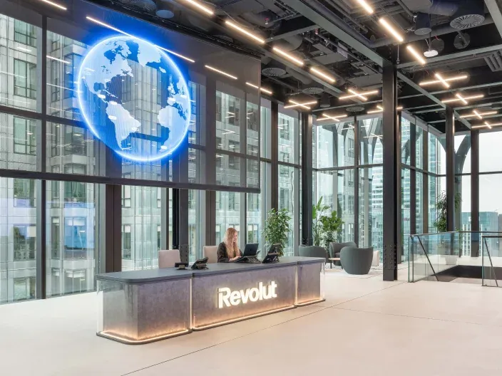 Recepción de oficinas de Revolut con diseño moderno y pantalla con globo digital.