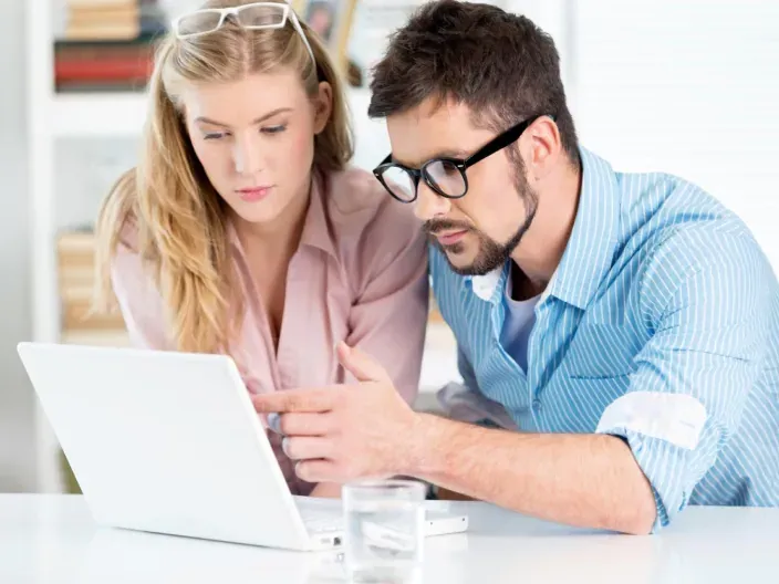 Pareja analizando un plan de ahorro o inversión en un ordenador portátil para gestionar sus finanzas.