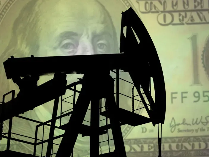 Silueta de torre de extracción de petróleo sobre un billete de cien dólares para representar el mercado energético global.