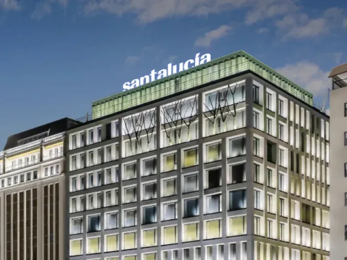 Sede corporativa moderna de Santalucía Seguros, con su fachada iluminada y el logo de la compañía en el tejado.