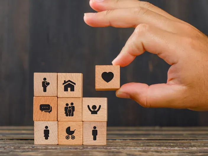 Mano construye un puzzle con iconos que representa seguro de vida, hogar y planificación.