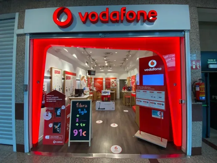 Exterior de una tienda Vodafone en España con escaparate iluminado y ofertas de fibra y móvil