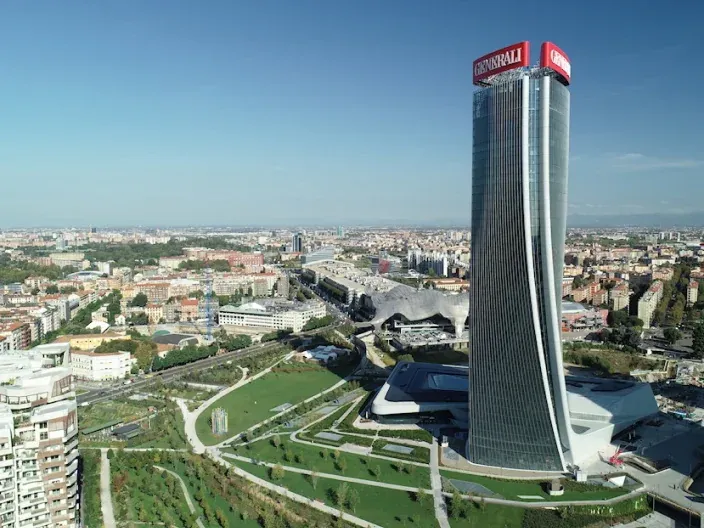 Vista aérea de la Torre Generali en Milán, un rascacielos icónico con un diseño moderno, destacando en el paisaje urbano.