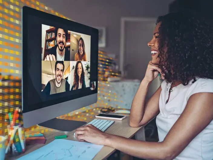 Mujer en videoconferencia grupal desde su iMac, simbolizando el teletrabajo y la conexión digital en el hogar.