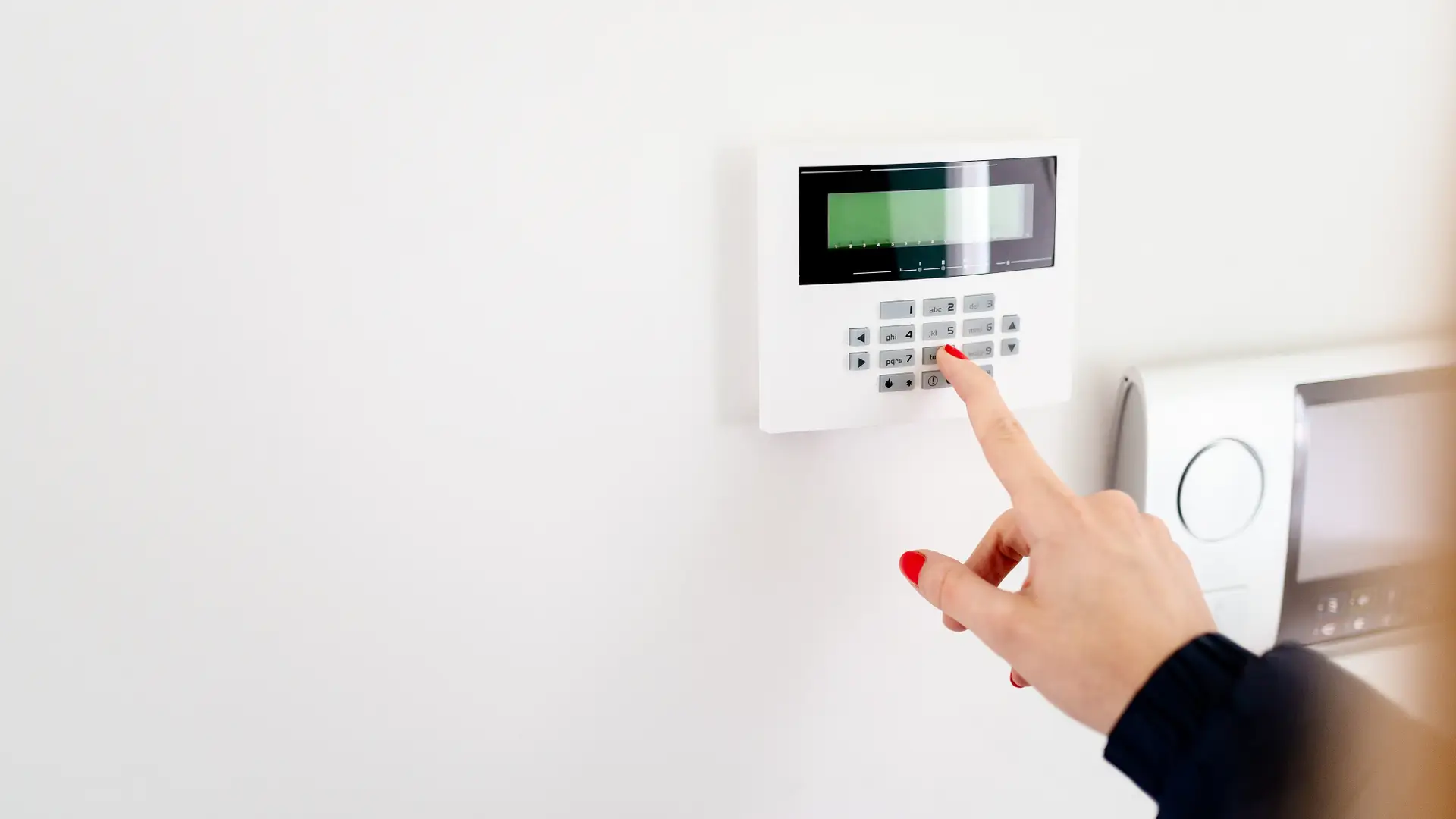 Persona desactivando alarma en panel de control de vivienda Persona desactivando alarma en panel de control de vivienda