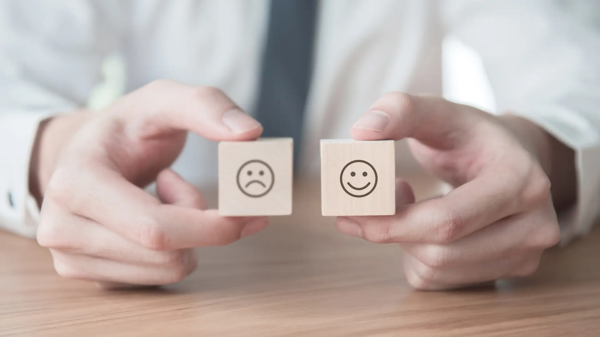 Hombre con dados de madera con cara enfadada y sonriente usadas para dar la opinión sobre las alarmas de hogar Hombre con dados de madera con cara enfadada y sonriente usadas para dar la opinión sobre las alarmas de hogar