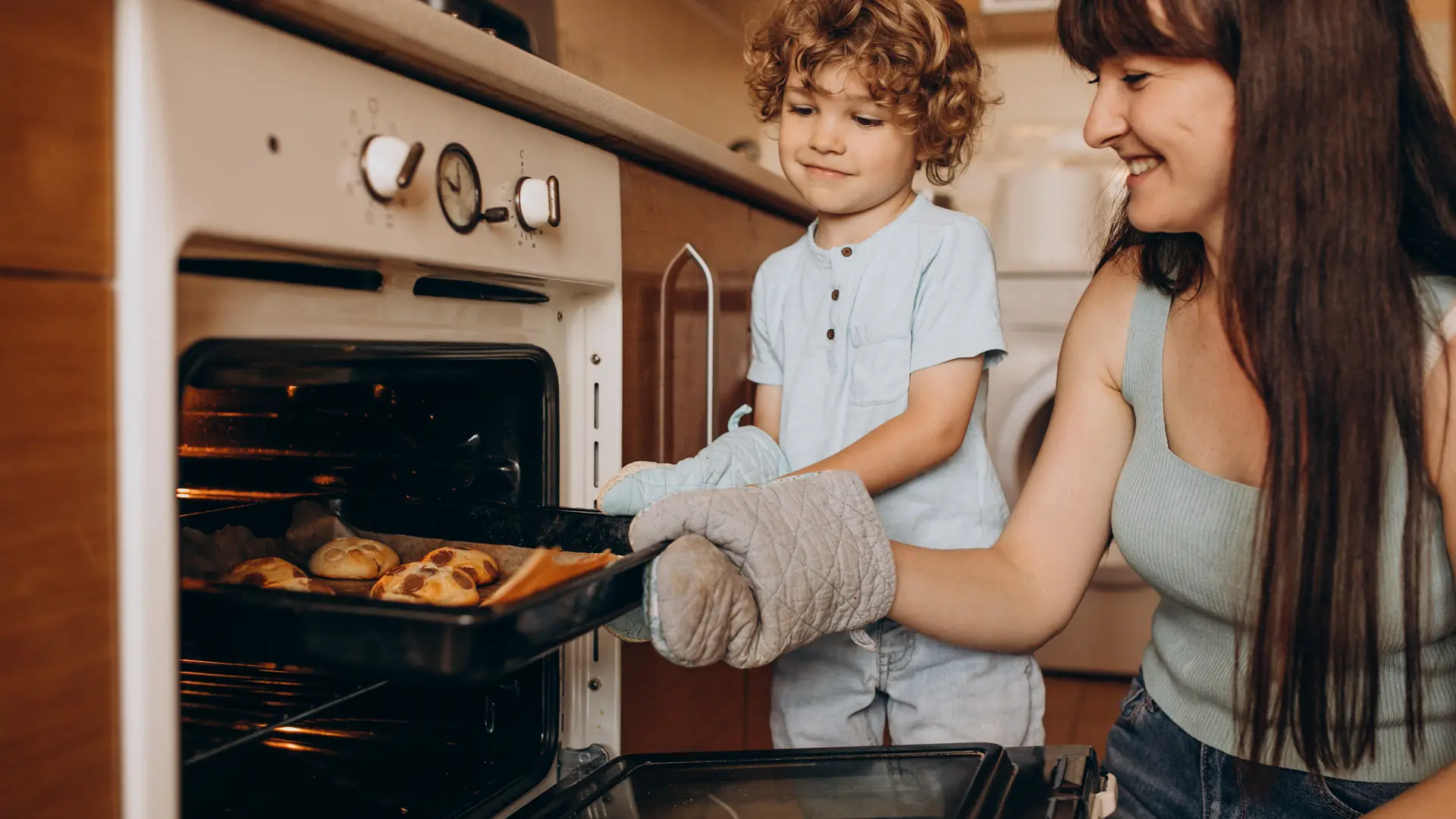Madre e hijo sacando magdalenas del horno, son clientes de la compañía eléctrica Eleia Madre e hijo sacando magdalenas del horno, son clientes de la compañía eléctrica Eleia