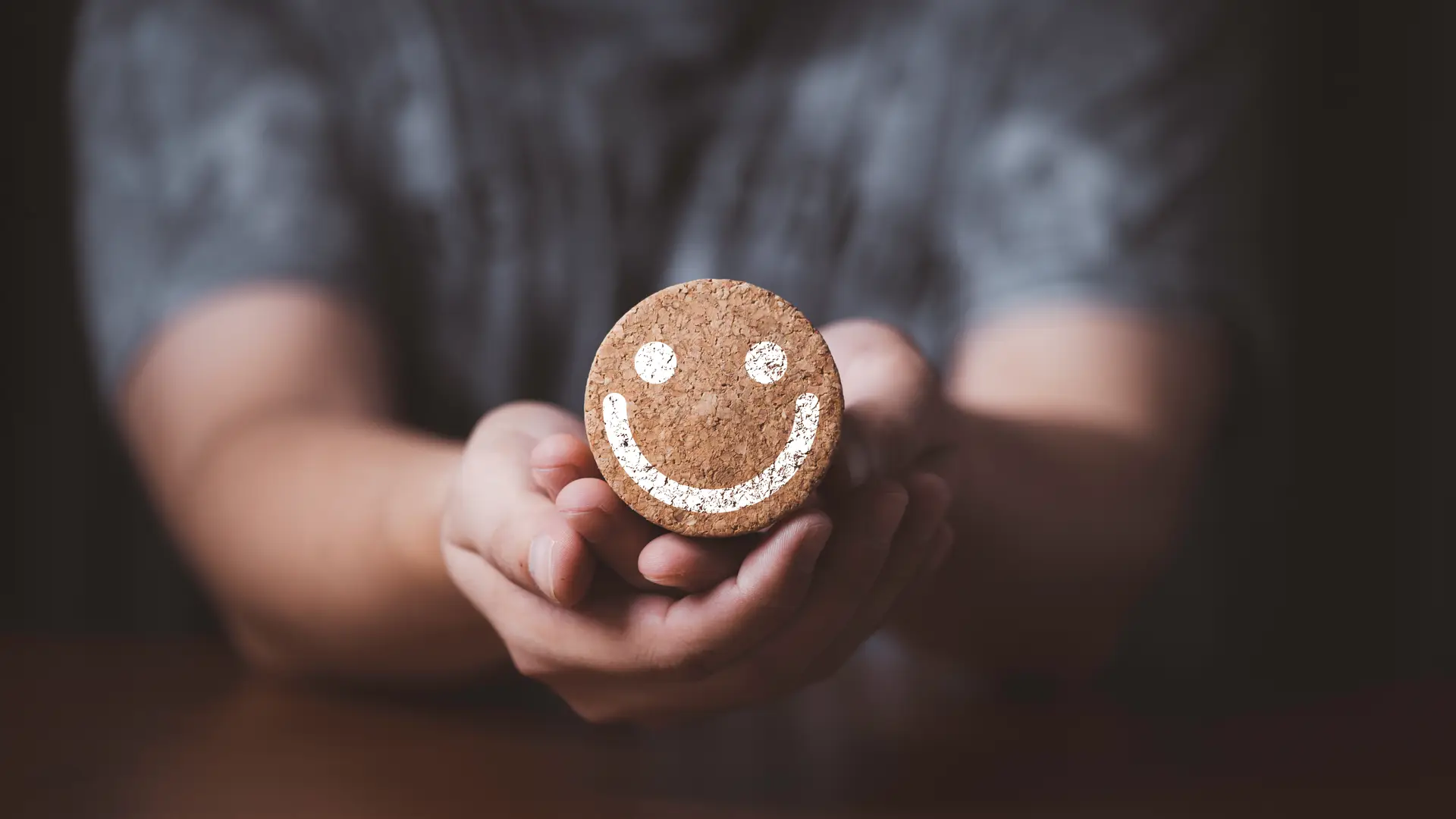 Persona sujetando un corcho con una carita sonriente representa las opiniones de los clientes de Eleia